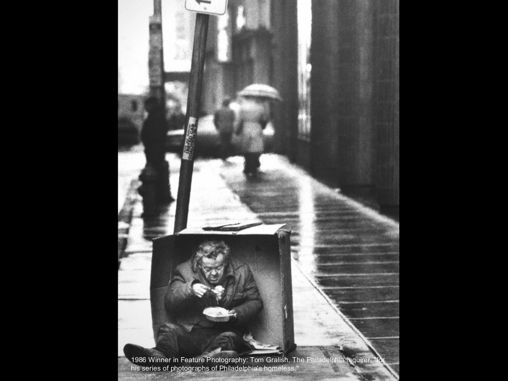 Pulitzer prize winning photo in 1986 by Tom Gralish – “Philadelphia’s Homeless.” Black and white photo of a Homeless man eating while sitting in a box.