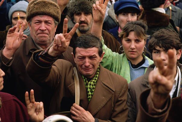 1990:  David C. Turnley – “The Romanian Revolution.”  Romanian people celebrating the end of communism with tears in their eyes and peace signs in the air.