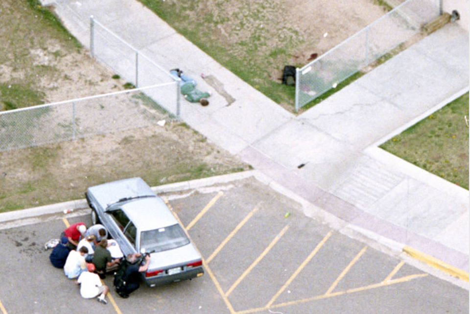 2000:  Photo Staff of the Rocky Mountain News – “Columbine School Shooting.”  The photo staff was awarded the Pulitzer in breaking news photography for a series of pictures documenting the shooting at Columbine High School as events unfolded.
Pictured above: Daniel Rohrbough lies dead on a sidewalk, soda from a can he dropped trickling downhill near him. At left, students crouch behind a car with a police officer who aims his gun at the school. (Rodolfo Gonzalez/Rocky Mountain News - April 20, 1999).