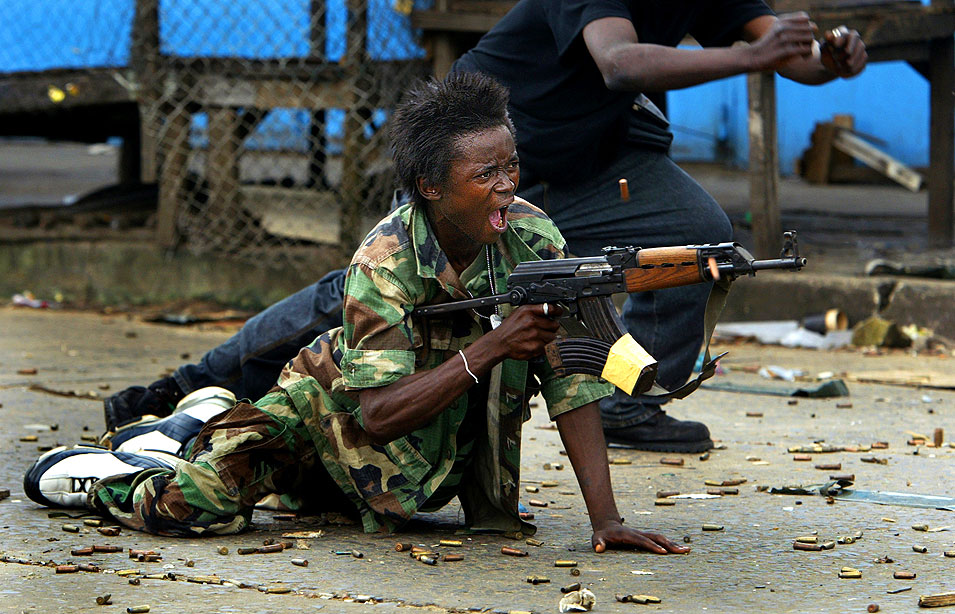 2004:  Carolyn Cole – “Second Liberian Civil War.”  For her cohesive, behind-the-scenes look at the effects of civil war in Liberia, with special attention to innocent citizens caught in the conflict, and child-soldiers.  This picture: “Firing Back.”  A government soldier defends a bridge in central Monrovia where a standoff between rebel and government forces held the city under siege.