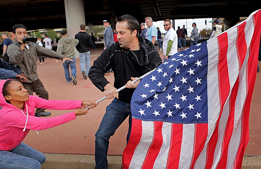2015 Picture 2:  Ferguson protester Cheyenne Green struggles to hold onto an American flag as a football fan makes a grab for it outside the Edward Jones Dome after a St. Louis Rams game.