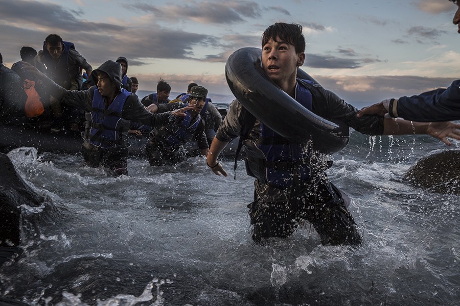 2016 Picture 2:  After battling rough seas and high winds from Turkey, migrants arrive by rubber raft on a jagged shoreline of the Greek island of Lesbos. Fearing capsize or puncture, some panicked and jumped into the cold water in desperation to reach land. This young boy made it, unlike hundreds of others