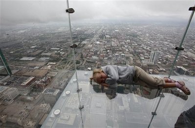 lays down on 'The Ledge,' the new glass balconies suspended 1,353 feet 412 meters in the air and jut out 4 feet 1.22 meters from the Sears Tower's 103rd floor Skydeck