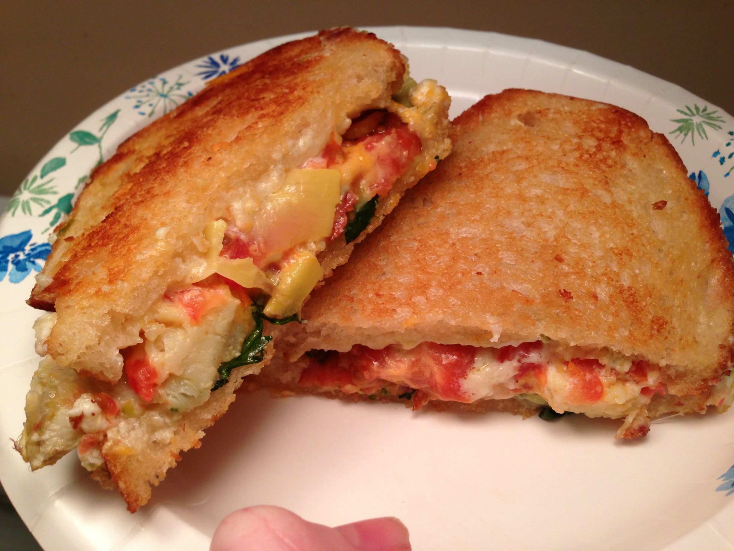 Overstuffed grilled cheese with cream cheese, cheddar, Parmesan, bacon, artichoke, jalapeno, tomato, and spinach