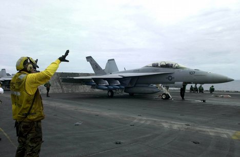 A V-1 Division aircraft director prepares an F-18 Super Hornet for launch.