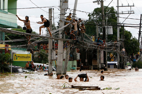 This is a picture of Philippine residents using power lines as a bridge in wake of the recent Typhoon Ketsana whore!. I assume there the power is out so it's relatively safe, or maybe they're just playing Filipino roulette.