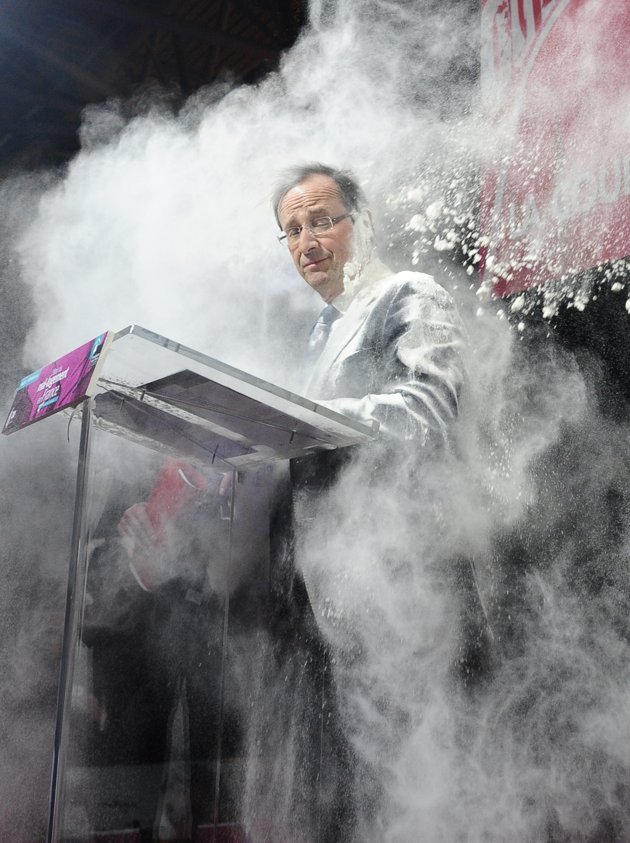 An unidentified woman throws flour on French Socialist Party candidate for the 2012 presidential elections, Francois Hollande, in Paris, Wednesday, Feb. 1, 2012. The woman ran to the side of the podium where Socialist Francois Hollande stood on Wednesday to sign a "social contract" in favor of housing for all.