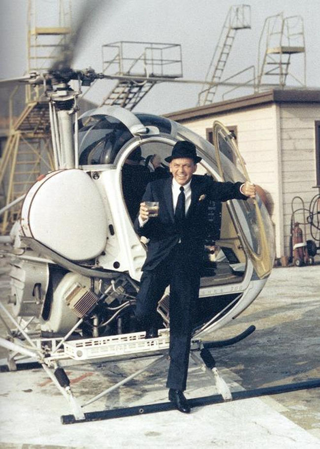 Frank Sinatra stepping out of a helicopter with a drink