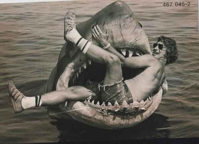 Steven Spielberg sitting in a mechanical shark used in the movie Jaws, 1974.