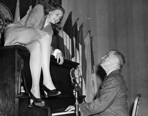 Lauren Bacall perched atop the piano as President Harry Truman plays it