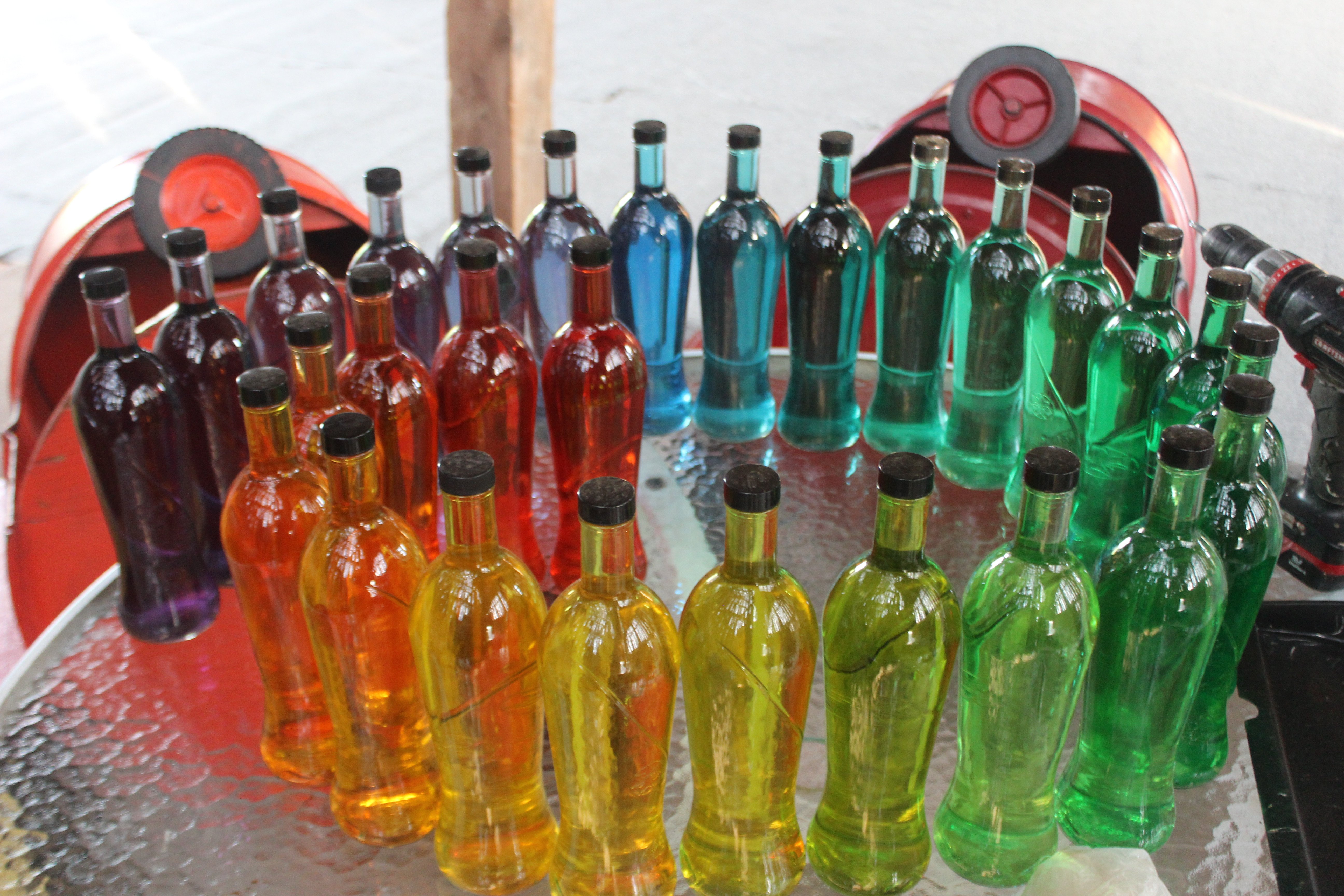 "So here are the bottles waiting to be emptied to the proper amounts. I think at this point I had adjusted the purple/blue transition. It's still not perfect, but it works. The red and orange barrels in the background are called "Barrels of Fun." They all hook together and get pulled behind our golf cart. Kids get to sit in them and ride around. I had lots of fun with them growing up and now my nephews love them too."