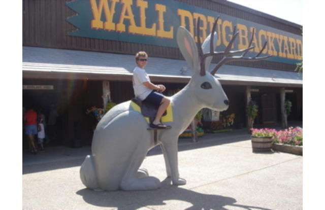 Man riding a statue of a rabbit with antlers in South Dakota.
