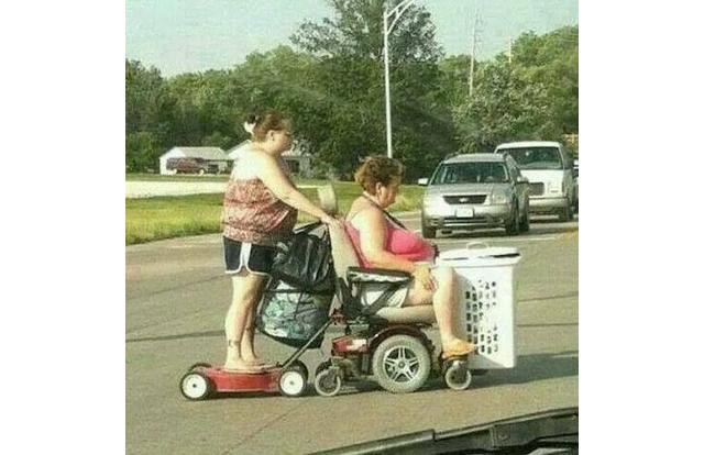 Woman on lawnmower being pulled by woman in a wheelchair in West Virginia.