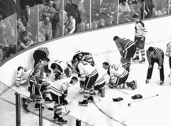 Players of the Toronto Maple Leafs and the Chicago Black Hawks search for Jack Evans’ lost contact lens during an ice hockey game, 1962.