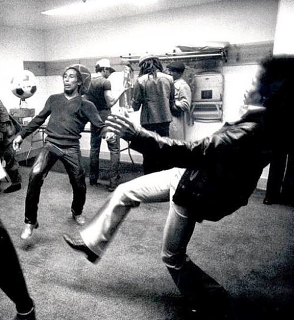 Bob Marley playing some soccer backstage .