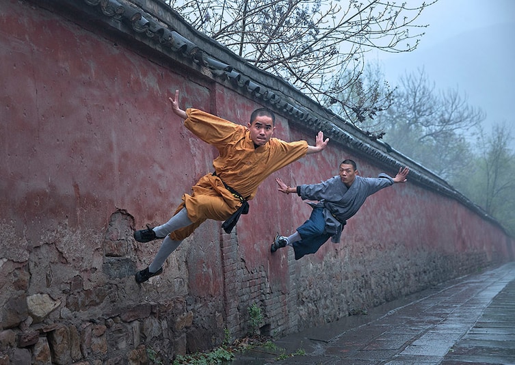 Shaolin monks run along a wall.   Professional Sport category.