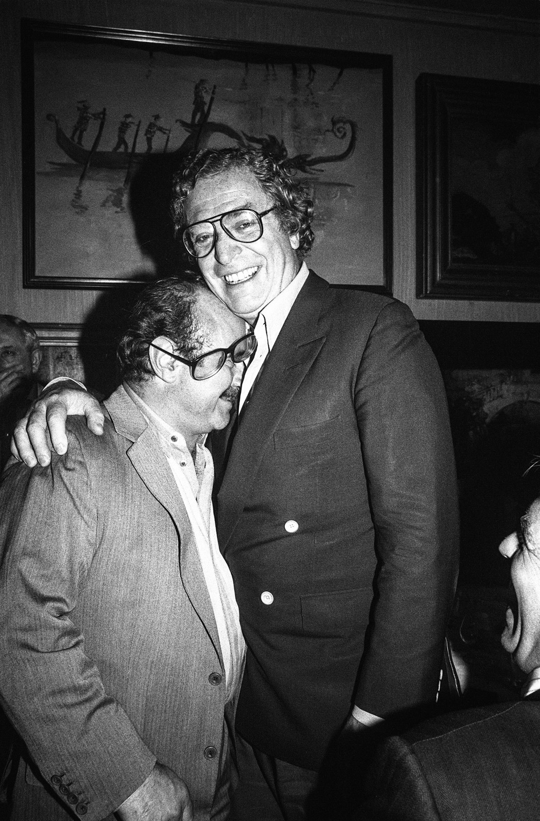 Bob Hoskins and Michael Caine have a big laugh knocking Hoskins glasses off as the 2 hang out with friends in the late 1970s.