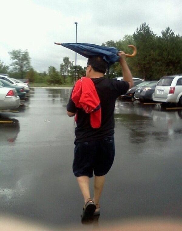 Person holding an umbrella over his head all wrong.