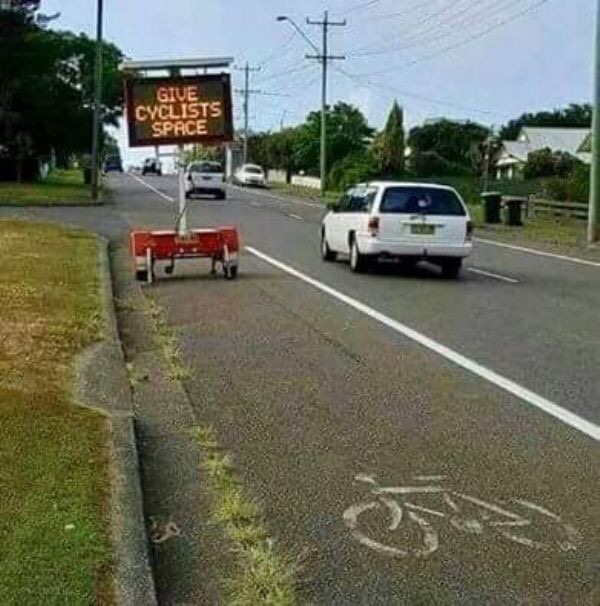 Sign asking to give cyclists space, smack right in the middle of where the cyclists need that space.