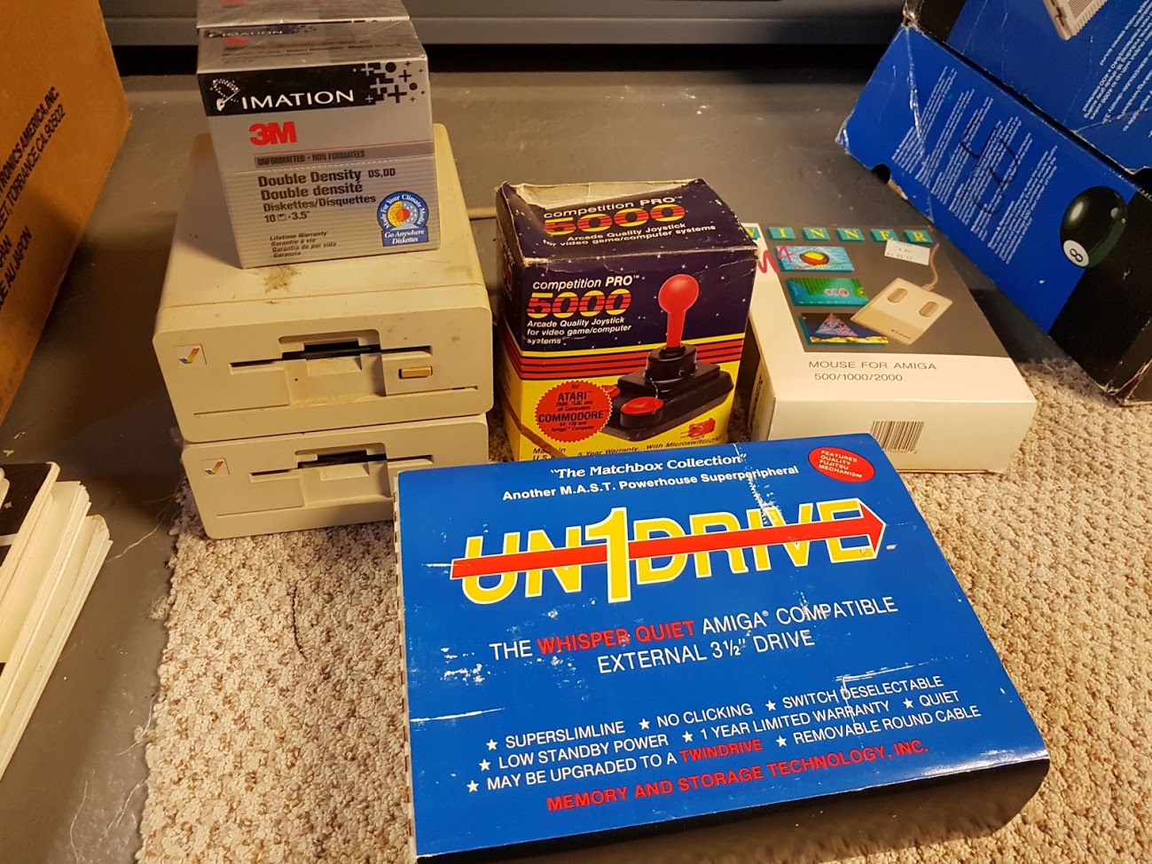 "Some more stuff. Two Amiga floppies and a generic external drive. Boxed joystick and a funny 3rd party mouse. Also, two unopened boxes of floppies."