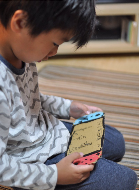 Turns out the kid in the picture made a cardboard Nintendo Switch, because he really wanted one, so his father decided to surprise him by buying one and doing what's on the right side of first picture. Then waiting to see how the kid would react.