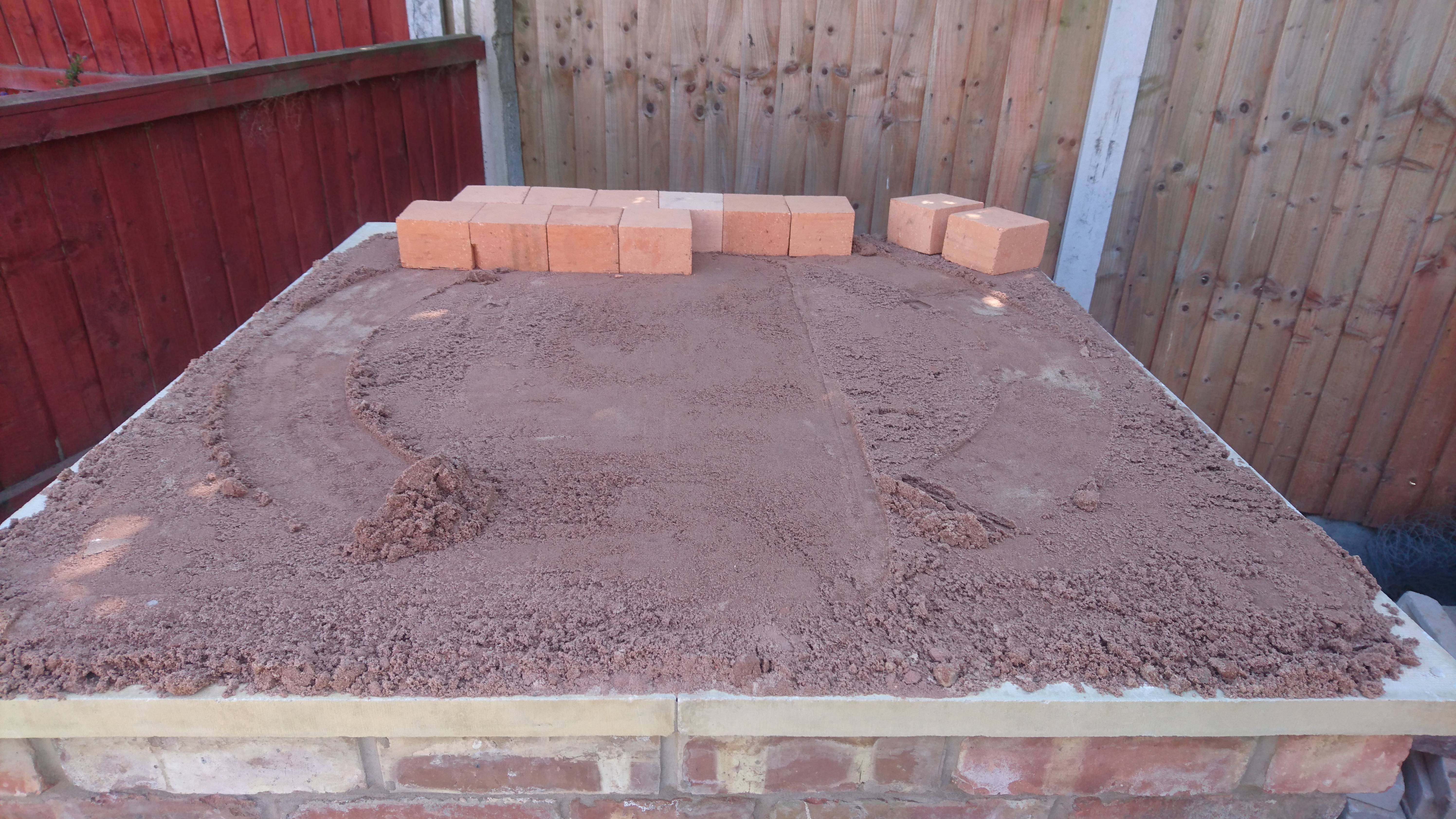 "Now to start the oven. Firstly, the oven floor. The entire oven must be constructed from fire proof bricks to ensure they dont break/crack from the very high temperatures. Lay sand over the top of the hearth and level out using the larger spirit level. The sand allows you to then make the oven floor bricks level with a rubber mallet. Using the trammel tool I faintly marked the outline of the oven wall on the sand, then created the floor making sure all of the outline is covered."