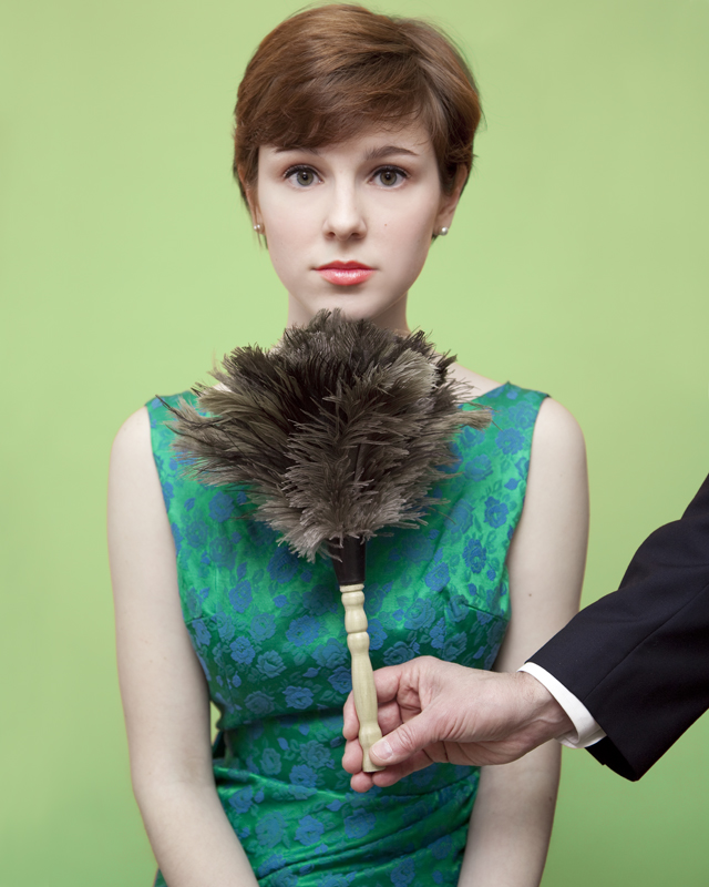 Red head woman with short hair getting tickled under her chin with a feather duster.