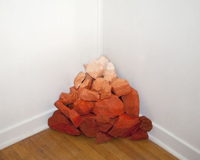 Pile of rocks in the corner of a room with wooden floors.