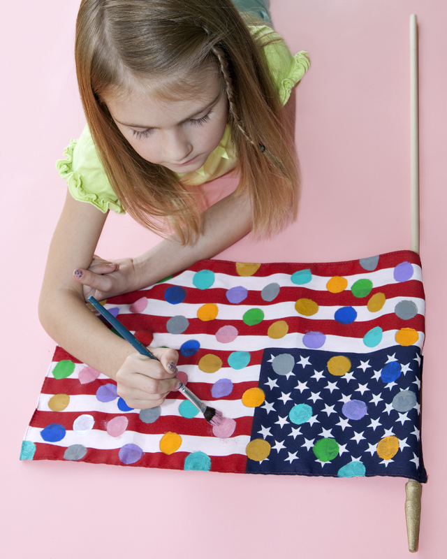 Girl placing polka dots on an American flag.