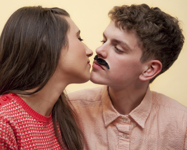man with a fake mustache kissing a woman
