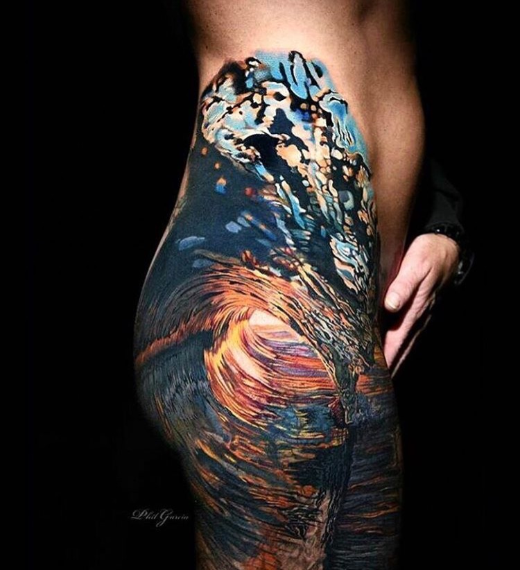 Tattoo on a woman's buttocks and leg of a cresting and crashing wave.