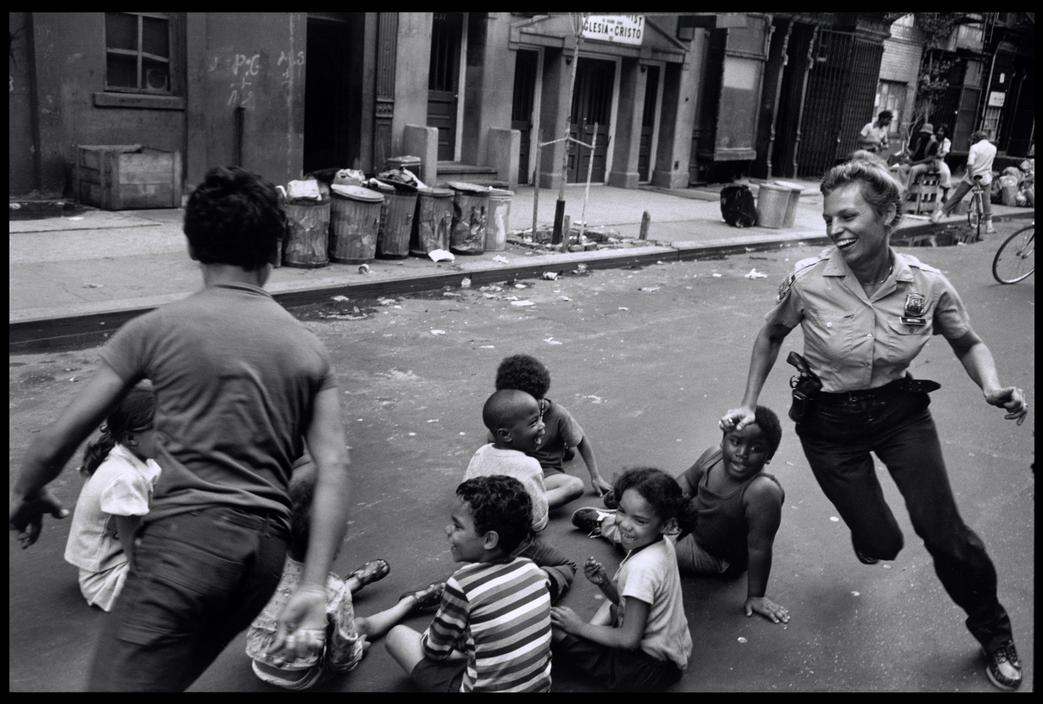 A police woman plays duck duck goose with children in Harlem, NYC, New York, US in 1978.