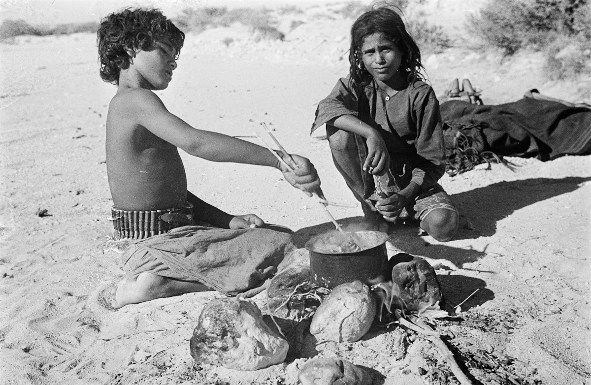 Two children prepare dinner for a small nomadic group (possibly all family) near the settlement of Ad Dibbin in Yemen in 1947.