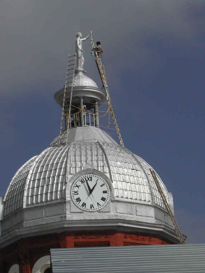 Fixing a statue on a dome by leaning a ladder against it.