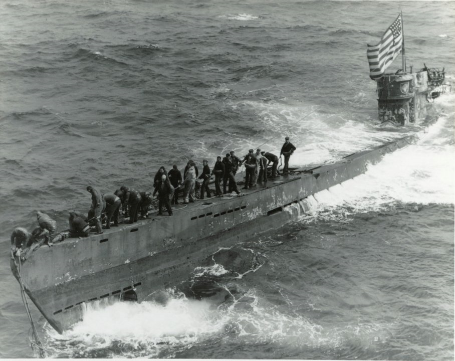 The crew of the USS Pillsbury secure a towing line to the captured U-505 in 1944. The U-boat was damaged by depth charges and thought to be sinking. The German crew thus abandoned it once surfaced. The escort USS Pillsbury saw the submarine and boarded her. They disabled explosives set to destroy the ship and plugged the holes, and were able to keep it afloat and salvage it. They captured an enigma machine, code books, and numerous other important items from this submarine.