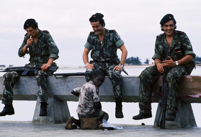 3 Portuguese soldiers laugh as a child shines their shoes in Angola in 1972. This was part of the Portuguese Colonial War that lasted 13 years until 1975. Despite at the time Portugal was winning the ongoing war, major political problems at home and increased pressure from other nations forced them to withdraw from Angola, Mozambique and Portuguese Guinea, eventually granting each nation their independence.