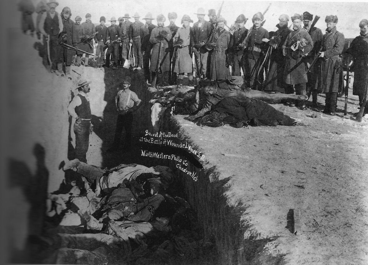 Soldiers pose for a picture at a mass grave site for the victims of the Wounded Knee Massacre in South Dakota, US, in 1890. The Lakota Sioux Native Americans had their lands seized by the US government for years, and armed conflicts had risen because of it. However, this group, led by Chief Spotted Elk, had moved to the reservation and were to be disarmed. They consisted of around 500 people, with half being women and children. During the weapons search and removal, a deaf warrior who did not speak English refused to disarm. When he got into a scuffle his weapon fired. At the same time, a medicine man was pumping up the warriors with a dance. Suddenly, a few warriors fired, and a small battle ensued. 500 armed troopers had all the Lakota Sioux surrounded at the time it began. Some 31 soldiers were killed, with another 33 wounded...