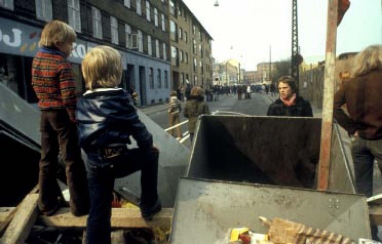 Children stand on makeshift barriers made by the local residents to protect a playground set for demolition in Copenhagen, Denmark in 1980. The area was considered a slum, and few public areas like the playground existed for the residents. The city ignored some 80% of the residents requesting to keep the playground, and set it for demolition. The residents responded with barriers and large crowds to halt incoming city work vehicles. The Copenhagen officials had to send in 800 policemen to clear the area to proceed. Small fights broke out with police causing a few injuries, with numerous people arrested.