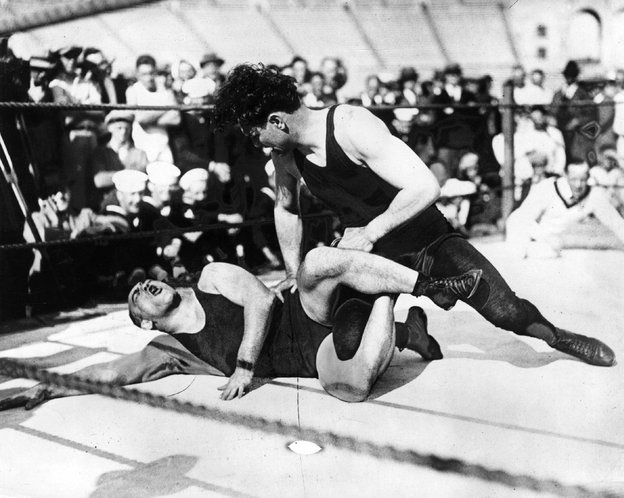 A wrestling match in NYC, US in 1926. Modern choreographed wrestling is nothing new. The fights and matches that entertain as a big production show has been around 150 years. Even many of the moves and outfits never changed.