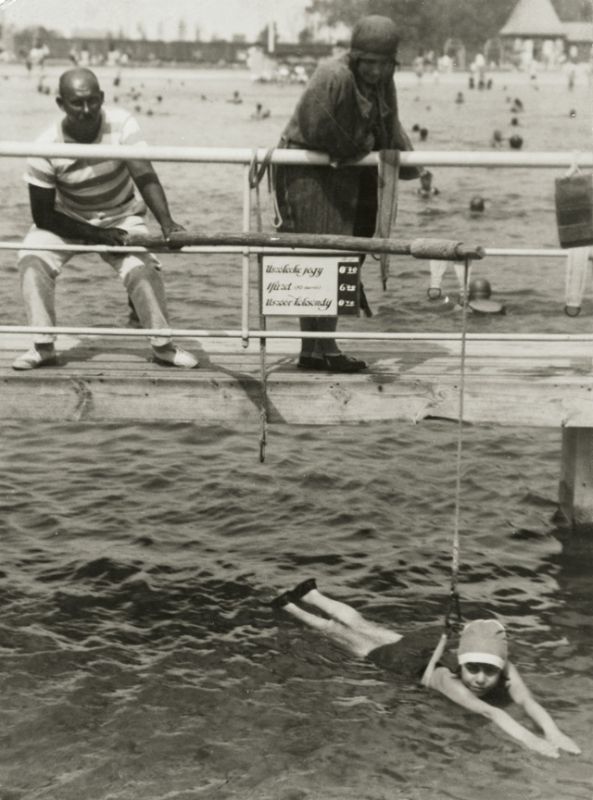 A young girl is getting swimming lessons on a French beach in 1908.