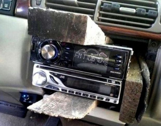 Redneck car repair of using wooden wedges to hold a car radio in place.