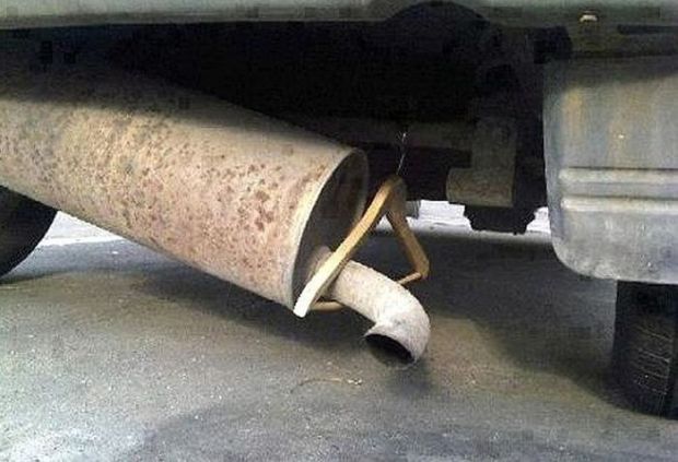 Redneck car repair of using a wooden hanger to keep muffler from dragging on the ground.