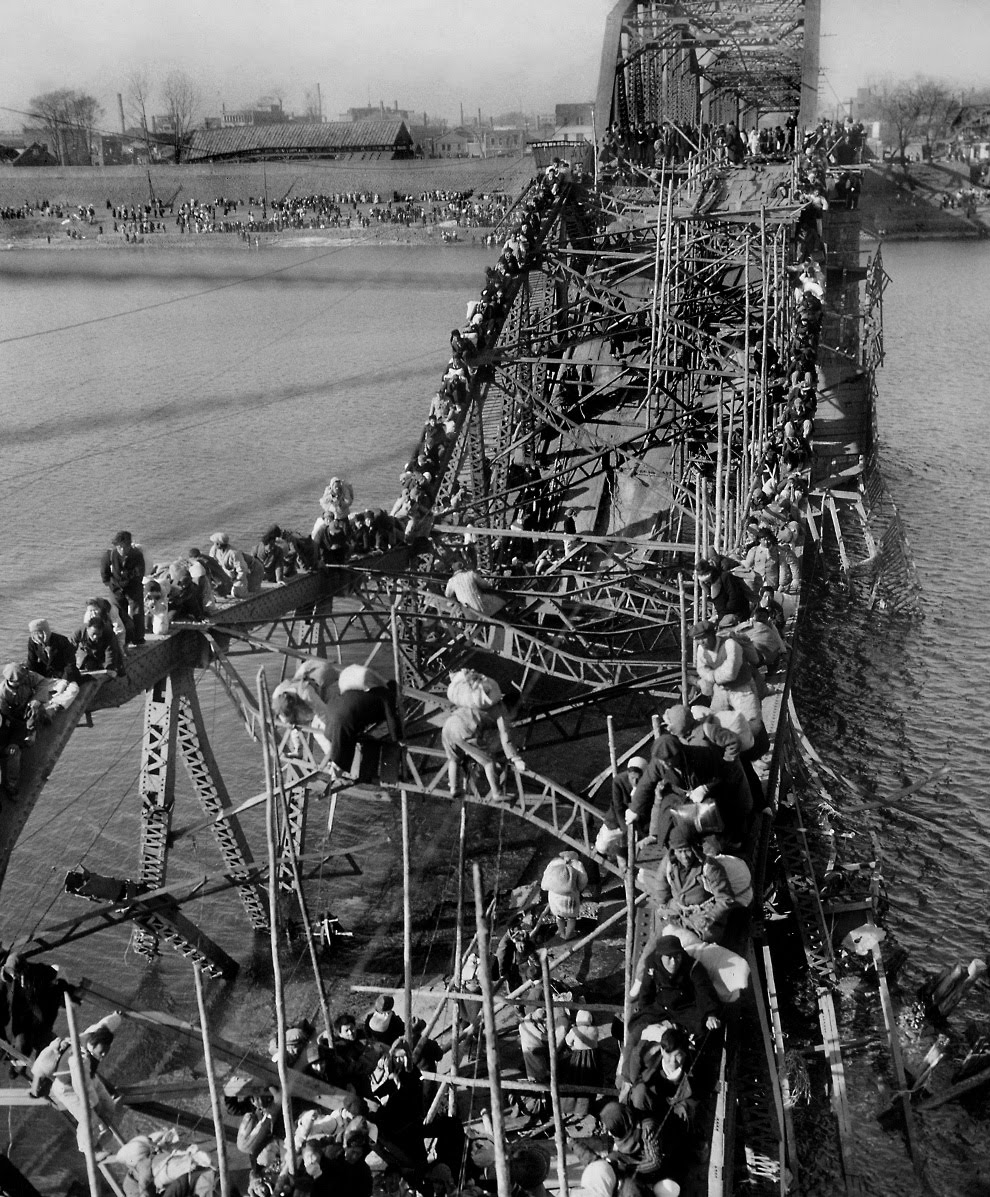 Residents of Pyongyang cross whats left of a bridge on the Taedong River to flee the advancing Chinese Communist troops in North Korea in 1950. North Korean invaded South Korea earlier that year, and took over most of the country. The US and its allies then landed, relieved the South and took over most of North Korean as well. This picture and the event was part of the massive US retreat after China entered the war, which pushed back the US and their allies to where the front lines became for the next 2 years before the fighting stopped. Those front lines would also be the current borders between the 2 nations. No Peace Treaty exists between North and South Korea, just a cease fire agreement that is still honored to this day, for now.