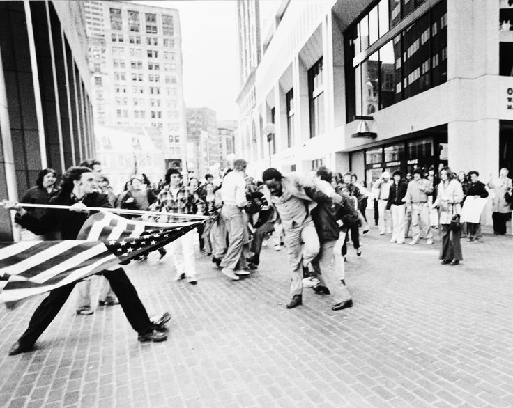 Continuing on with the unrest in Boston over desegregation, this picture in 1976 was taken of another person, Joseph Rakes, using the American flag in a far worse way than the child above. This prize winning picture called "The Soiling of Old Glory" shows people attacking black lawyer and activist Ted Landsmark who had helped lobby for the desegregation and integration of the busing system. The picture appears to show Rakes trying to stab Landsmark, but the pole is longer than the picture shows. He was actually swinging the pole, trying to hit Landsmark instead, and in fact would entirely miss him. Landsmark was bloodied in the assault all the same by the other attackers. Rakes was arrested, but despite being convicted and sentences to 2 years in prison for his assault, the sentence was suspended. Most activism stopped by 1980 as desegregation became a mainstay. However, fearing future unrest, the court ordered mandate for desegregation in Boston did not expire until 1988.