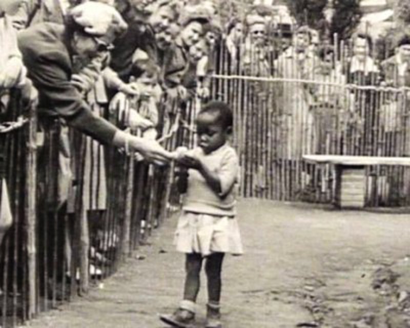 A woman feeds an African child in Belgium in 1958. This was at the last known public human zoo. That's right, an African family resides within the fence and Belgians watch them and feed them as if they are animals.
