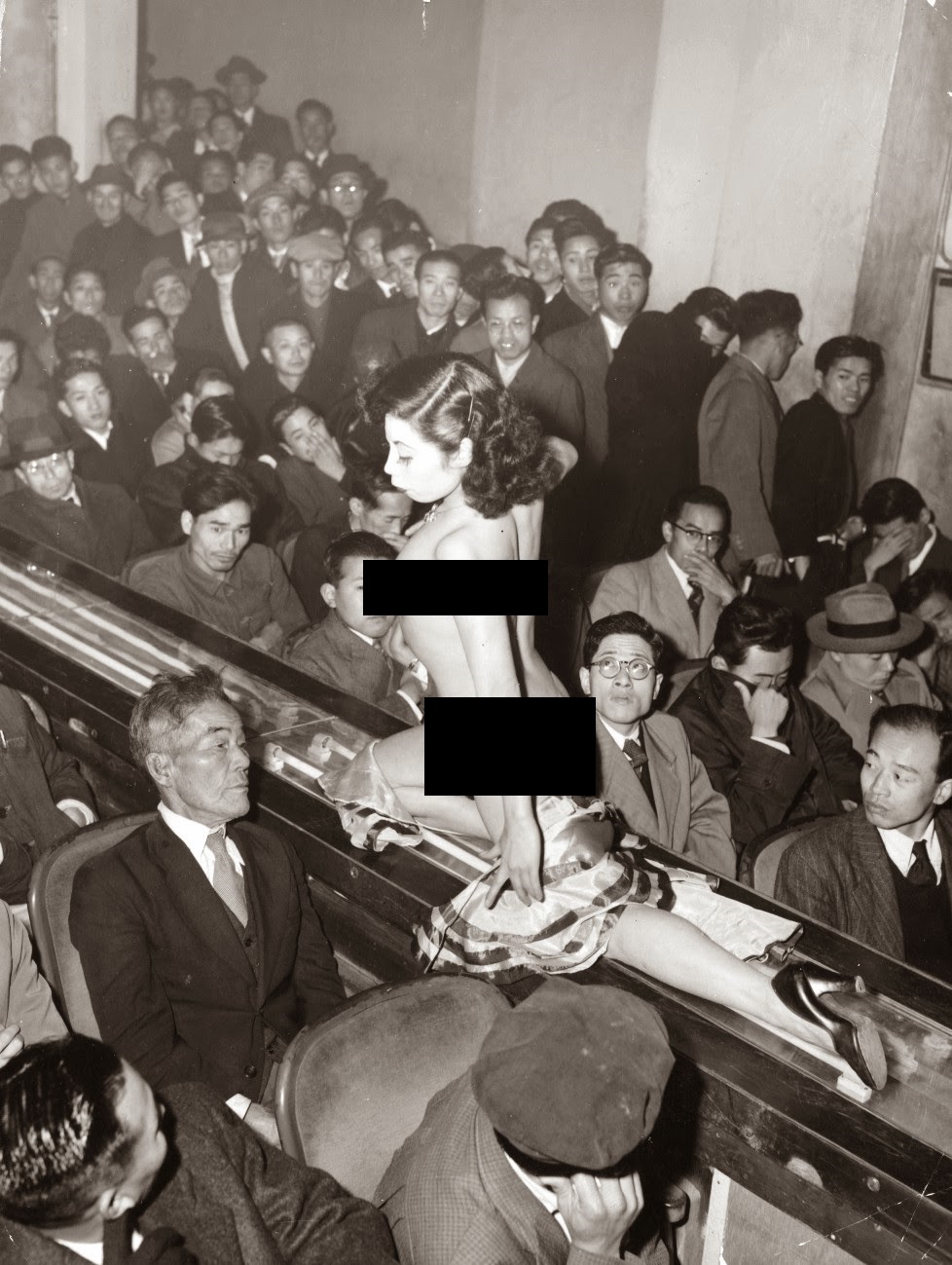 A stripper at a striptease show is taken past the audience on a moving conveyor belt in Tokyo, Japan in 1957. After WWII, Japanese culture opened up immensely. Everything from cars to electronics to unique ways of sexual gratification engulfed the populace, expanding them into world leaders in each category by the late 1970s.