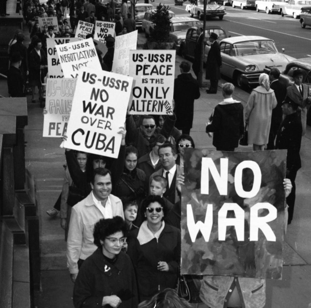 People take to the streets in Washinton D.C., US to protest against any aggression that could lead to war during the Cuban Missile Crisis in 1962. The Soviets wanted to put nuclear missiles in Cuba for first strike capabilities against the US in the event of war. Cuba, having gone communist with Castro rising to power, would be blockaded, and a 13 day standoff took place. Interesting note, the US saw the missiles well before they could be fired, and chose not to destroy them. This was a decision John F Kennedy made, against the wishes of virtually every military advisor he had. This allowed the missiles to become operational and also the possibility of half the East Coast to be destroyed. War was averted at the last minute through back door channels that had both countries disarm and remove missiles in key locations (Cuba for the USSR and Turkey for the US).