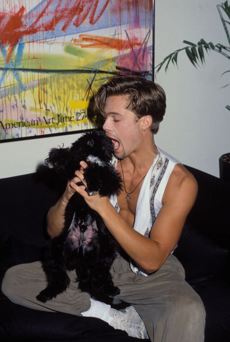 Brad Pitt goofing off with the photographers dog during a photo shoot in LA, US in 1989. Pitt did many shoots in the late 1980s, sporting many different looks. He wore his glasses, had many different haircuts, anything to get noticed as he was broke and scrounging for work. He did finally get noticed, and had a small parts in a few films, including Thelma and Louise, which kick-started his super successful career.