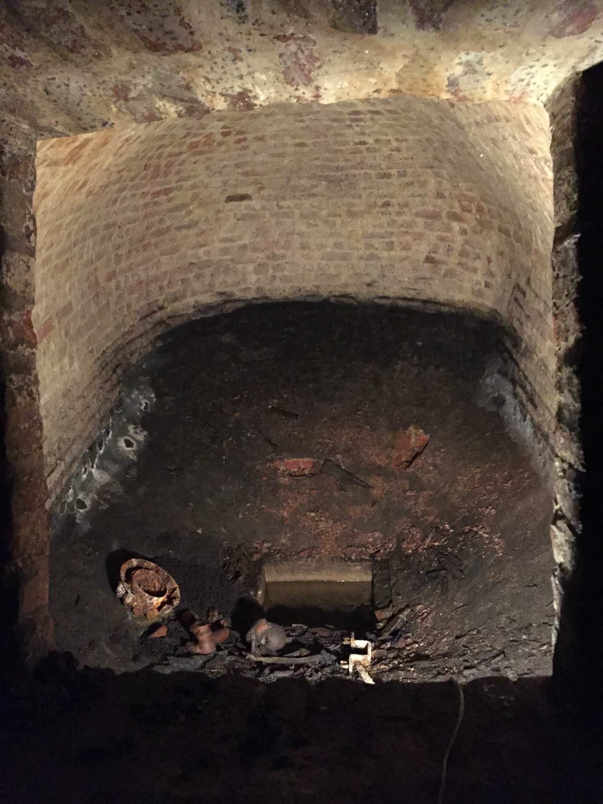 "At the other side of the coal chute there is a larger vaulted room. The room is accessible only through a wide rectangular opening in the wall. The bottom of the opening came up to my hips and i'm 194cm (6'4 in freedom units). Very nice masonry. Vaulted basically everywhere, there is no horizontal floor. This could be a sort of water reserve/water pit from the time of the brewery in the 17th century. You can see tools (?) laying around and a square hole in the middle with water in it. What is the purpose? I don't know."