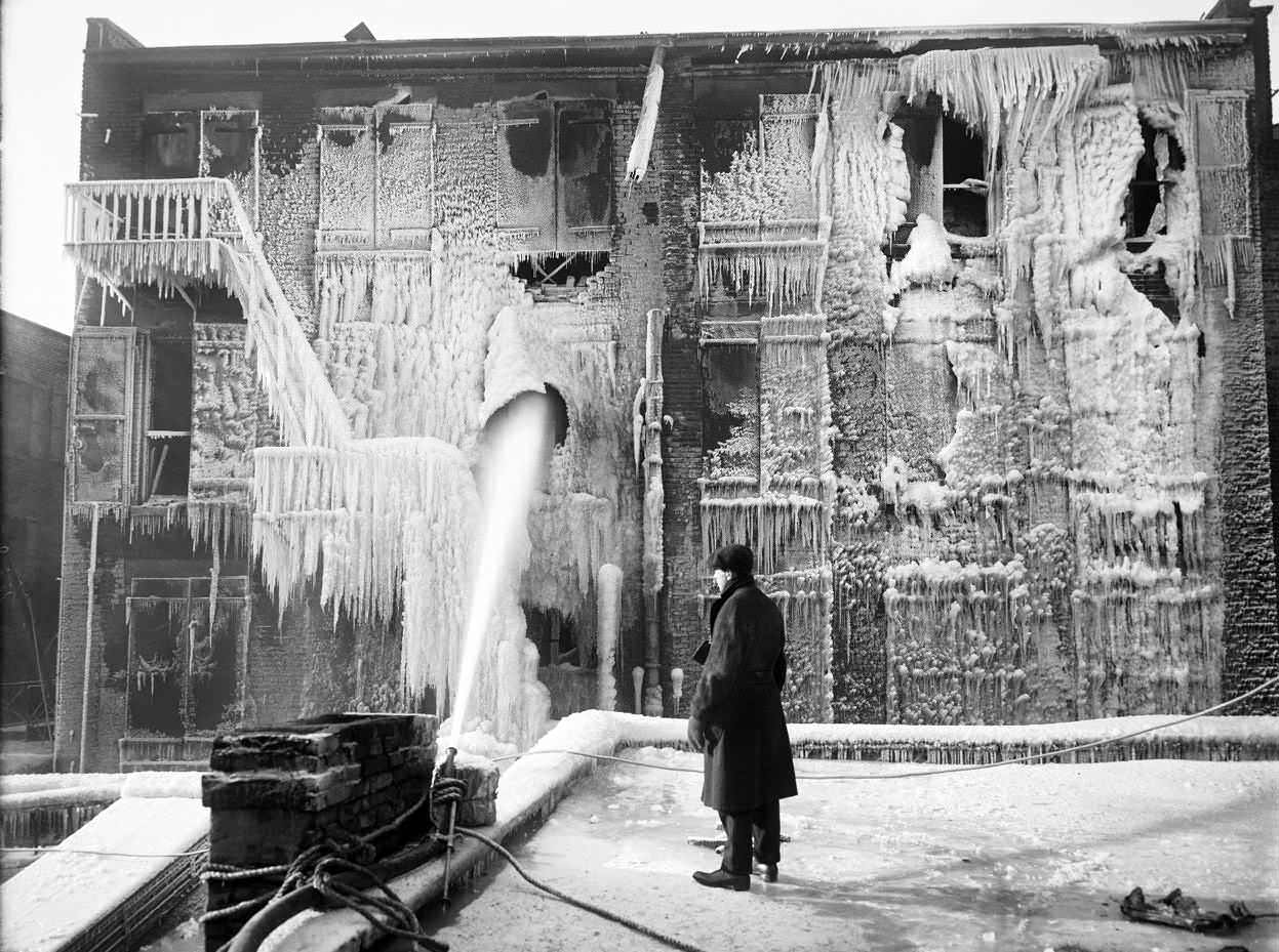 A man looking on as a fire hose makes sure a fire is out in New York City, US in 1917. As you can see, it is so cold out that most of the water almost immediately turned to ice, creating this unique image.